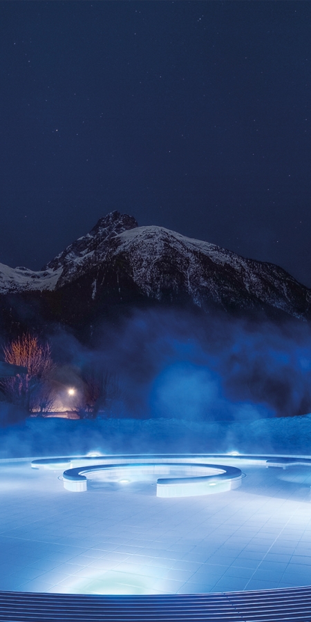 Stimmungsvoller Blick auf das beleuchtete Aussenbecken des Bogn Engiadina in Scuol im Winter