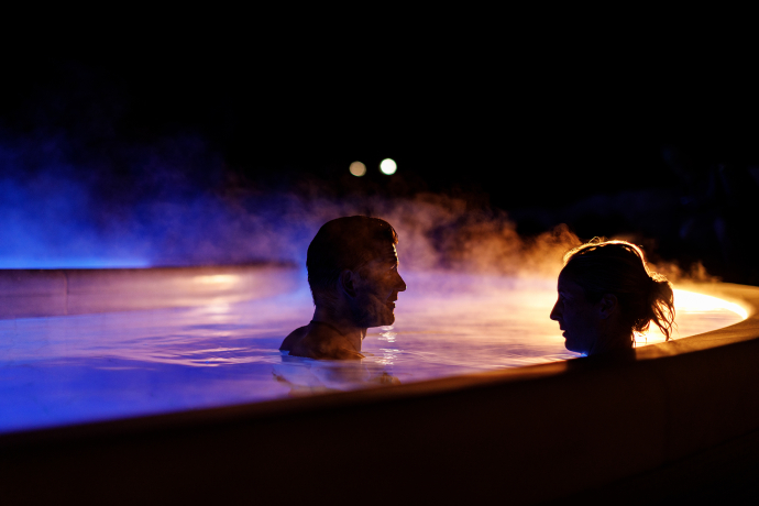 Zwei Personen entspannen am Abend im Aussenbad des Bogn Engiadina Scuol  Zwei Personen entspannen am Abend im Aussenbad des Bogn Engiadina Scuol
